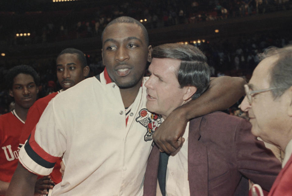 FILE - Louisville's Robbie Vallentin hugs coach Denny Crum after beating Auburn 84-76 for the West NCAA Championship in Houston, March 21, 1986. Denny Crum, who won two NCAA men’s basketball championships and built Louisville into one of the 1980s’ dominant programs during a Hall of Fame coaching career, died Tuesday, May 9, 2023. He was 86.(AP Photo/RC, File)