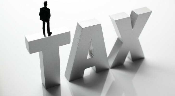 Man standing on a large letters that spell "TAX"