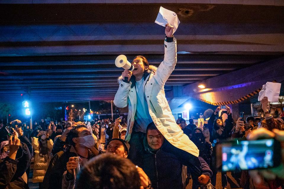 2022年11月28日，北京的示威活動中，一名示威者舉著白紙並高喊口號。在街頭和大學校園，反對封控的抗議蔓延中國各地。