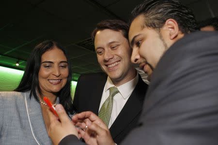 Georgia State Senator (D-Decatur), and gubernatorial candidate Jason Carter (C), checks out a cell phone picture with Pastor Blanca Domingez (L) and Antonio Molina after speaking at a private event in Tucker, Georgia May 23, 2014. REUTERS/Tami Chappell