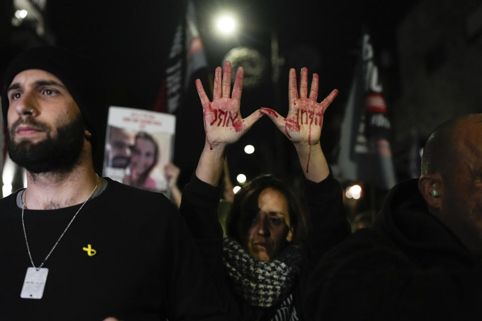 FILE - Relatives and supporters of the Israeli hostages held in the Gaza Strip by the Hamas militant group attend a protest calling for their release outside the Knesset, Israel's parliament, in Jerusalem, Monday, Jan. 22, 2024. Hebrew on the hands with fake blood reads, "Time is running out". After the Oct. 7 attack by Hamas, Israelis put aside their differences and rallied behind the war effort in Gaza. But as the war grinds on, the mood of the Israeli public is shifting and old divisions are reemerging. The catalyst is a rift over the polarizing leadership of Israeli Prime Minister Benjamin Netanyahu and a growing frustration with his management of the war. (AP Photo/Ohad Zwigenberg, File)