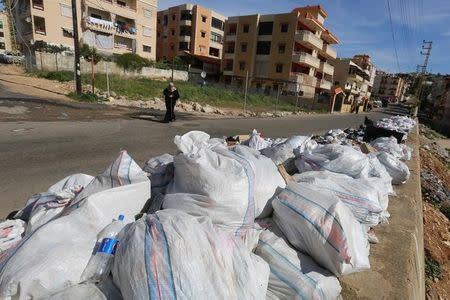 A woman covers her nose as she walks past garbage near residential buildings in Wadi al-Zayneh, Chouf district, Lebanon January 28, 2016. Picture taken January 28, 2016. REUTERS/Aziz Taher