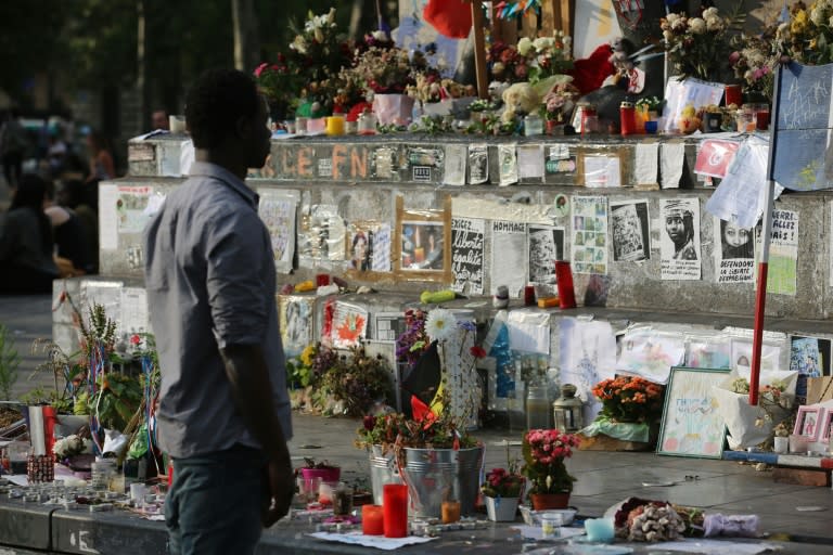 A man stands in front of French flags and messages displayed in Paris on July 26, 2016 after a priest was killed in the Normandy city of Saint-Etienne-du-Rouvray