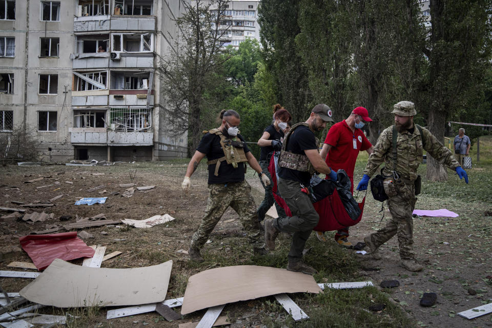 Paramedics carry the body of a woman who was killed during a Russian bombardment at a residential neighborhood in Kharkiv, Ukraine, on Thursday, July 7, 2022. (AP Photo/Evgeniy Maloletka)