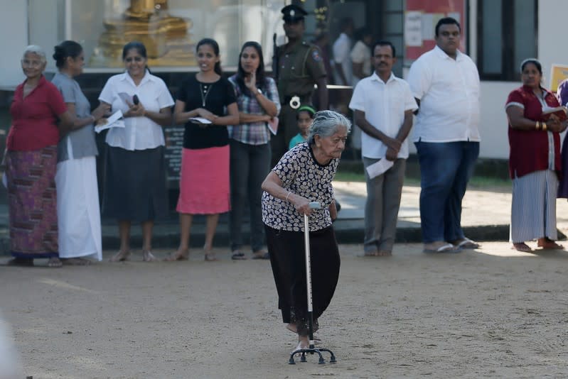 An old woman leaves a polling station after casting her vote during the presidential election in Colombo