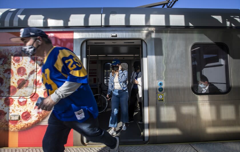 Inglewood, CA - January 30: A Rams fan runs out to catch a shuttle bus from the Metro C Line Hawthorne/Lennox station to SoFi Stadium Sunday, Jan. 30, 2022 in Inglewood, CA. (Brian van der Brug / Los Angeles Times)