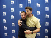 In this May 3, 2019, photo, Aaron Ruell, who played the character Kip, left, and Jon Heder, who played Napoleon Dynamite, hug during a photo-op as they celebrate the 15th anniversary of the cult classic comedy "Napoleon Dynamite," in Salt Lake City. (AP Photo/Rick Bowmer)