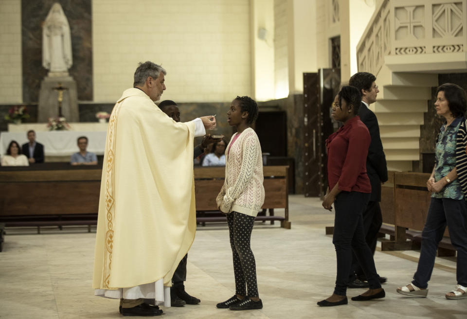 Father Giorgio gives communion during an early evening mass at the cathedral, which Pope Francis will visit later this week, in the capital Maputo, Mozambique Tuesday, Sept. 3, 2019. Pope Francis heads this week to the southern African nations of Mozambique, Madagascar and Mauritius, visiting some of the world's poorest countries in a region hard hit by some of his biggest concerns: conflict, corruption and climate change. (AP Photo/Ben Curtis)