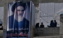 In this Saturday, Feb. 1, 2020 photo, a poster of Grand Ayatollah Ali al-Sistani is on display with Arabic that reads, "Peace, father of Iraq," in Tahrir Square, Baghdad, Iraq. Al-Sistani, Iraq’s top Shiite cleric, turns 90 this year, and when he recently had surgery it sent chills around the country and beyond. What happens when al-Sistani is gone? Iran is likely to try to exploit the void to gain followers among Iraq’s Shiites. Standing in its way is the Hawza, the centuries-old institution of religious learning which al-Sistani heads and which follows its own tradition-bound rules. (AP Photo/Khalid Mohammed)