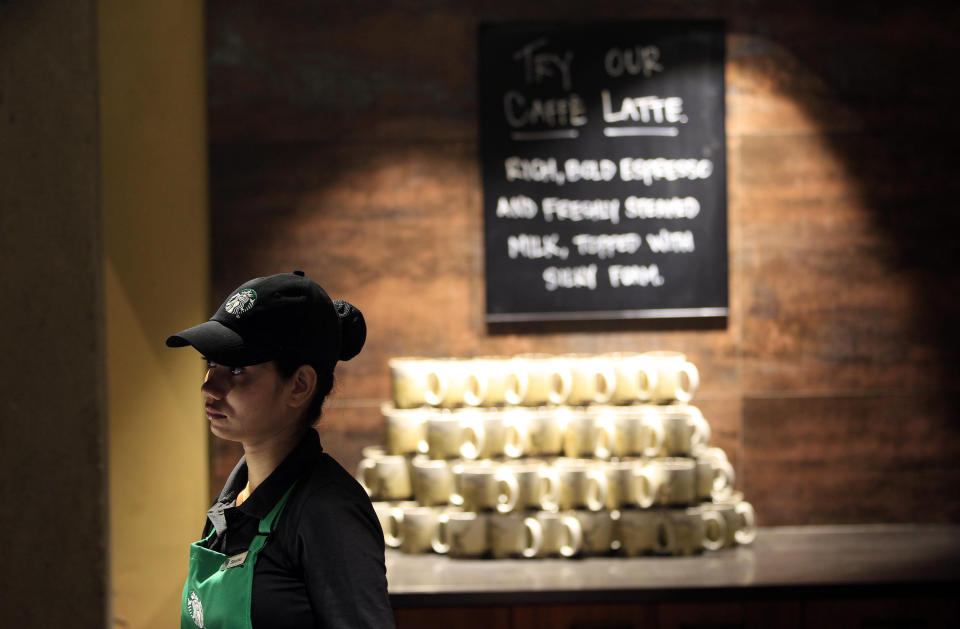 An Indian employee of the newly inaugurated first India outlet of Starbucks stands at the store in Mumbai, India, Friday, Oct. 19, 2012. Starbucks inaugurated its first store in India Friday in a historic building in southern Mumbai as the Seattle-based coffee giant seeks growth in a market long associated with tea drinkers. (AP Photo/Rajanish Kakade)