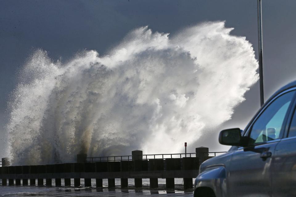 Powerful waves crash against the sea wall overflowing onto Ocean Boulevard at Hampton Beach as cars crawl past Wednesday morning Jan. 10, 2024.