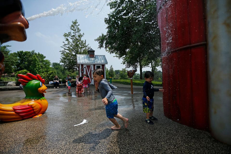 Sterling DeCilles, 4, (left) runs with his little brother, Judah, 2, on the splash pad at Juilfs Park in Anderson Township, Ohio, on Monday, June 13, 2022.