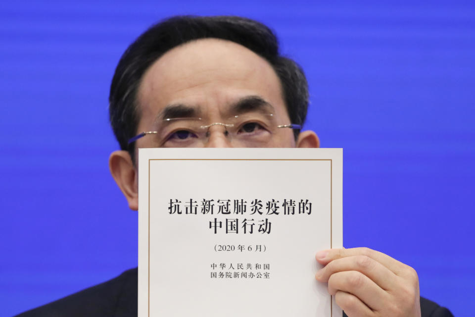 Xu Lin, Vice head of the Publicity Department of Communist Party shows a copy of the white paper on fighting COVID-19 China in action during a press conference at the State Council Information Office in Beijing, Sunday, June 7, 2020. Senior Chinese health officials defended their country's response to the new coronavirus pandemic, saying they provided information in a timely and transparent manner. (AP Photo/Andy Wong)