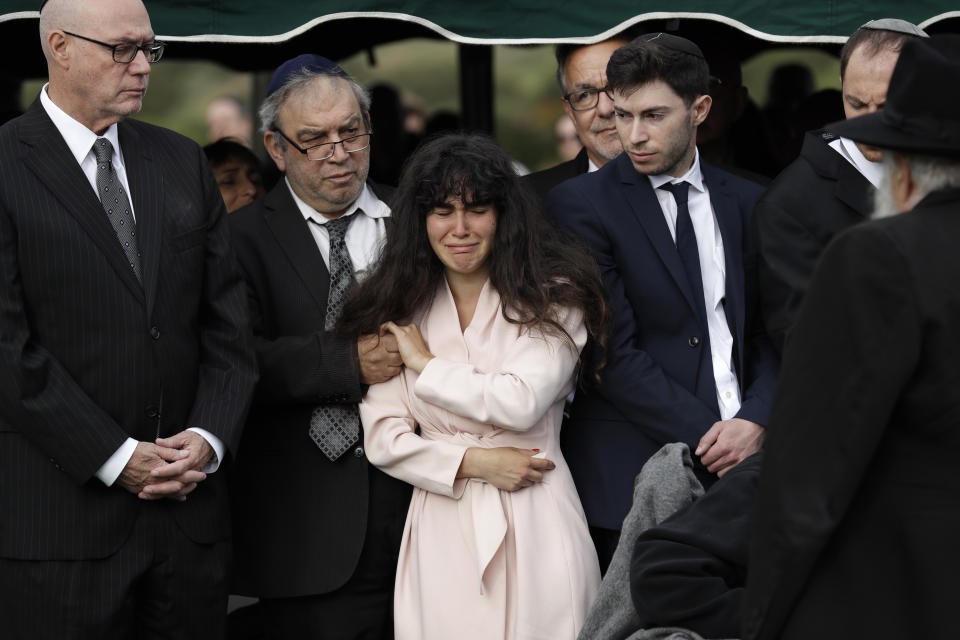 Hannah Kaye, the daughter of shooting victim Lori Kaye, center, holds the hand of her father, Howard Kaye, during funeral services, Monday, April 29, 2019, in San Diego. Lori Kaye was killed when a man opened fire several days earlier inside a synagogue near San Diego, as worshippers celebrated the last day of a major Jewish holiday. (AP Photo/Gregory Bull)