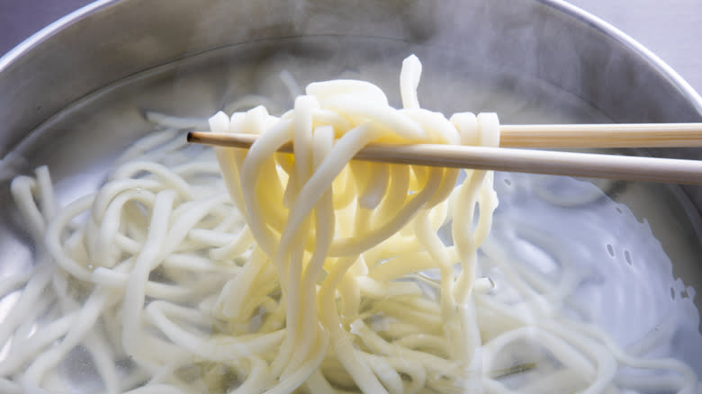 Udon noodles boiling and chopsticks