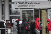 People waiting to be vaccinated queue up at the entrance to the Covid-19 vaccination centre at the Frankfurt exhibition grounds in Frankfurt, Germany, Tuesday, Nov. 30, 2021. Nevertheless, the city of Frankfurt sees its vaccination campaign thwarted by a lack of vaccine. Although the vaccination campaigns of the public health department were very well received by the citizens and the demand had recently increased strongly, the city now had to limit its vaccination offers - because the vaccine quantities ordered by the public health department had been unilaterally reduced by the federal government, the public health department announced on Monday. (Arne Dedert/dpa via AP)