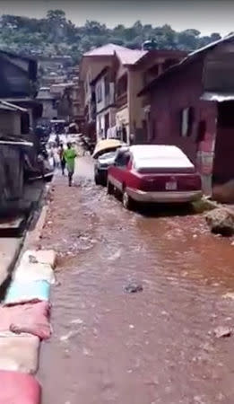 Residents commute though floodwater in the town of Foulah, following Monday's mudslide on the outskirts of Freetown, Sierra Leone, in this still image obtained from a social media video taken August 15, 2017. Kelvin Kamara and Fuhard Sesay / Social Media Website via REUTERS