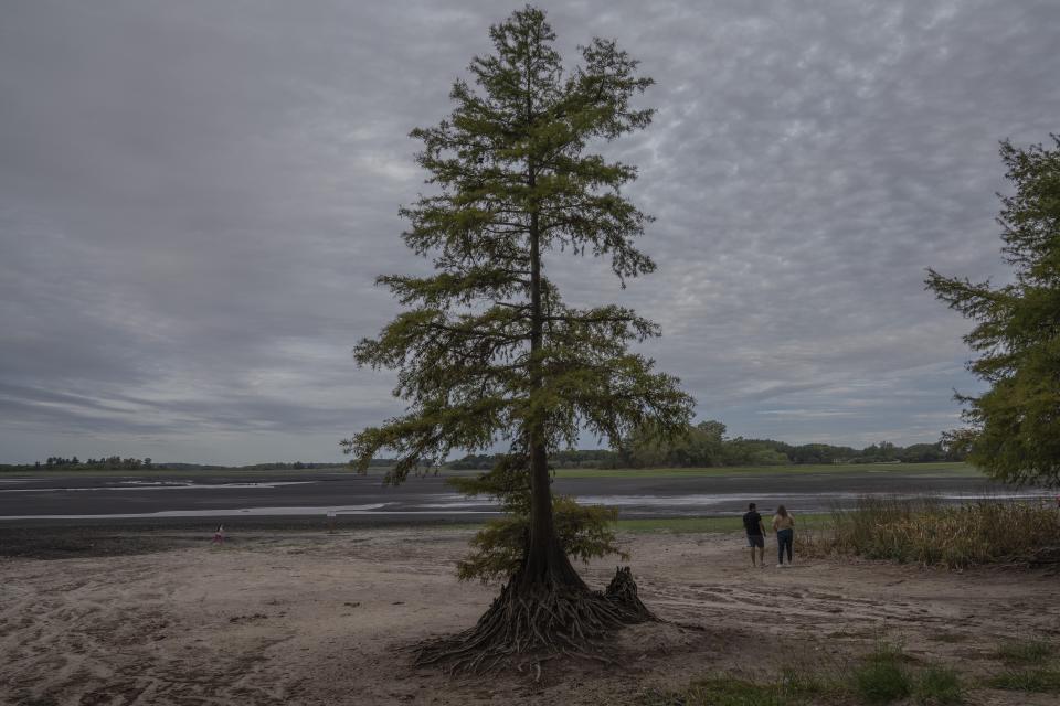 Los visitantes observan el lecho seco del lago de la represa Canelón Grande que proporciona agua potable a Montevideo en Canelones, Uruguay, el martes 21 de marzo de 2023. (AP Foto/Matilde Campodonico).