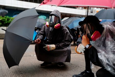Anti-government protesters take cover while riot police use rubber bullets to disperse them during a demonstration following a government's ban on face masks under emergency law, at Prince Edward, in Hong Kong