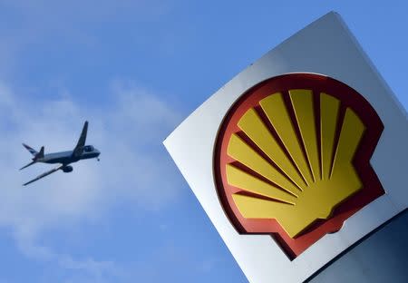 A passenger plane flies over a Shell logo at a petrol station in west London, in this January 29, 2015 file photo. REUTERS/Toby Melville/Files