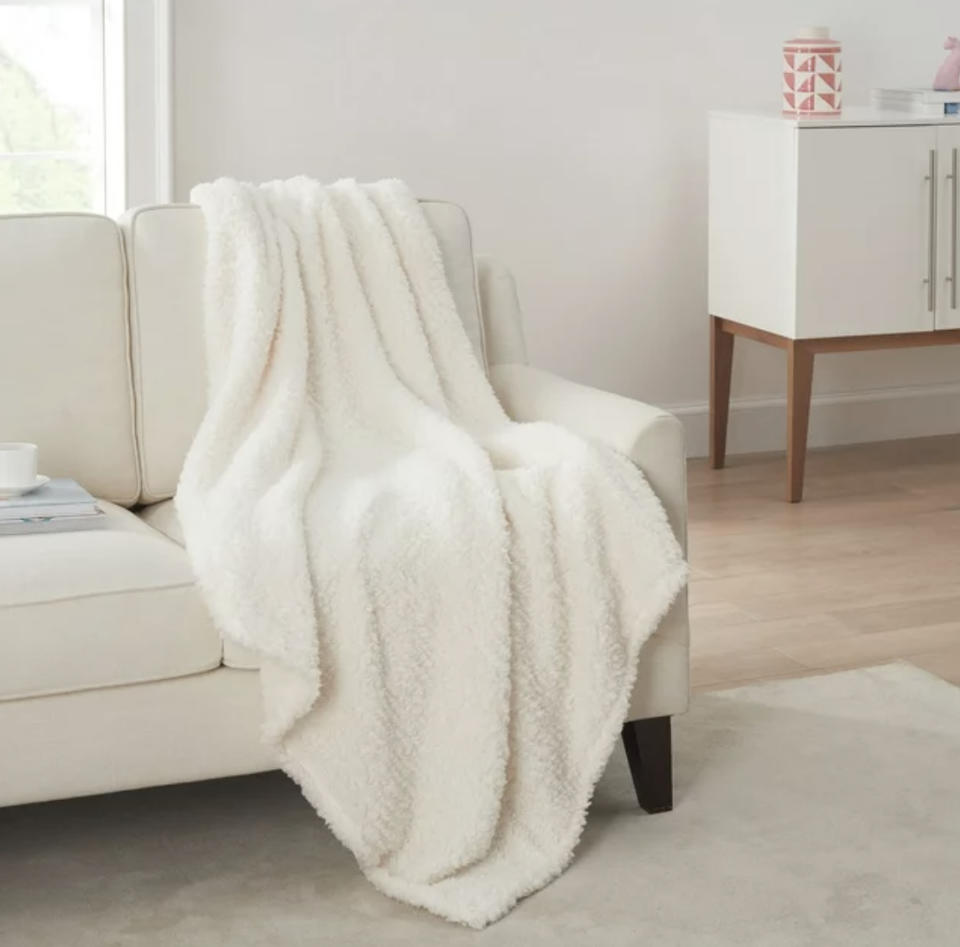 Plush white blanket draped over a beige sofa in a living room setting