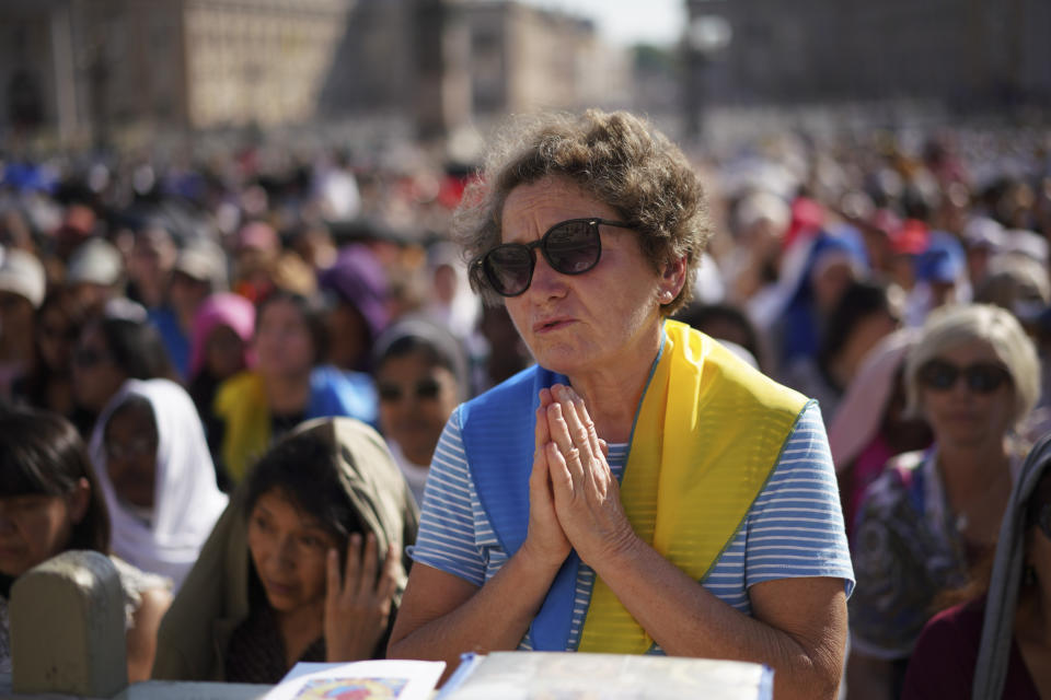 A woman prays as Pope Francis celebrates Mass on the occasion of the Migrant and Refugee World Day, in St. Peter's Square, at the Vatican, Sunday, Sept. 29, 2019. (AP Photo/Andrew Medichini)