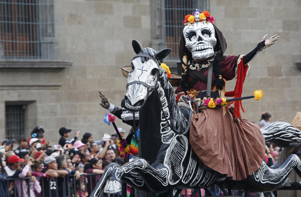 A performer in costume attends a Day of the Dead parade in Mexico City, Sunday, Oct. 27, 2019. The parade on Sunday marks the fourth consecutive year that the city has borrowed props from the opening scene of the James Bond film, "Spectre," in which Daniel Craig's title character dons a skull mask as he makes his way through a crowd of revelers. (AP Photo/Ginnette Riquelme)