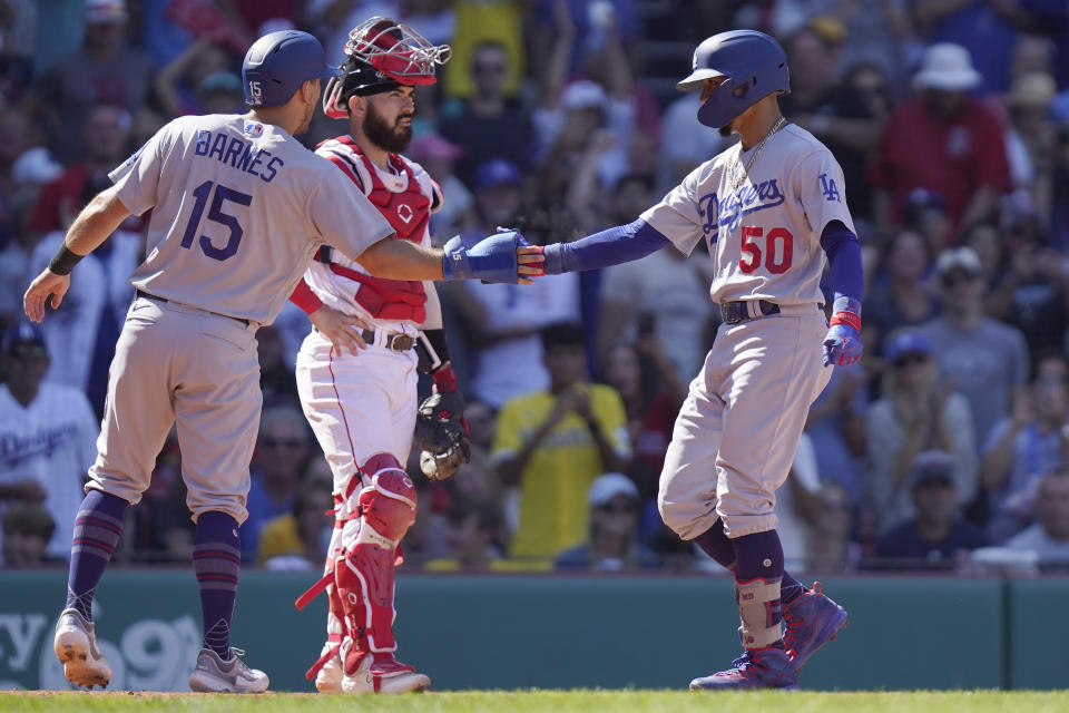 Los Angeles Dodgers' Mookie Betts (50) celebrates with Austin Barnes (15) as Boston Red Sox catcher Connor Wong, center, looks on after Betts hit a two-run home run allowing Barnes to score in the sixth inning of a baseball game, Sunday, Aug. 27, 2023, in Boston. (AP Photo/Steven Senne)