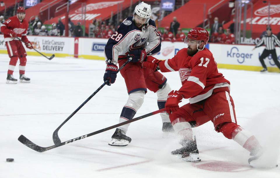 Detroit Red Wings defenseman Filip Hronek (17) steals the puck from Columbus Blue Jackets right wing Oliver Bjorkstrand (28) during the first period of an NHL hockey game Tuesday, Jan. 19, 2021, in Detroit. (AP Photo/Duane Burleson)