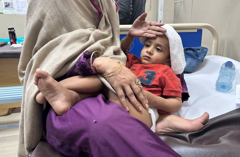 Ayaan Ali lies on his mother's lap in the emergency room at Sir Ganga Ram hospital in Lahore