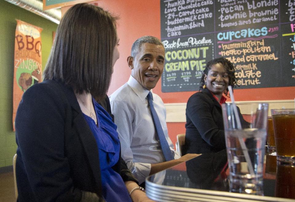 President Barack Obama sits between Mira Friedlander, a 22 year old senior at the University of Michigan, left, and Aisha Turner, 36, a mother of three who has worked for nearly two decades as a server as he has lunch at Zingerman's Deli in Ann Arbor, Mich., Wednesday, April 2, 2014, before speaking at the University of Michigan about his proposal to raise the national minimum wage. (AP Photo/Carolyn Kaster)