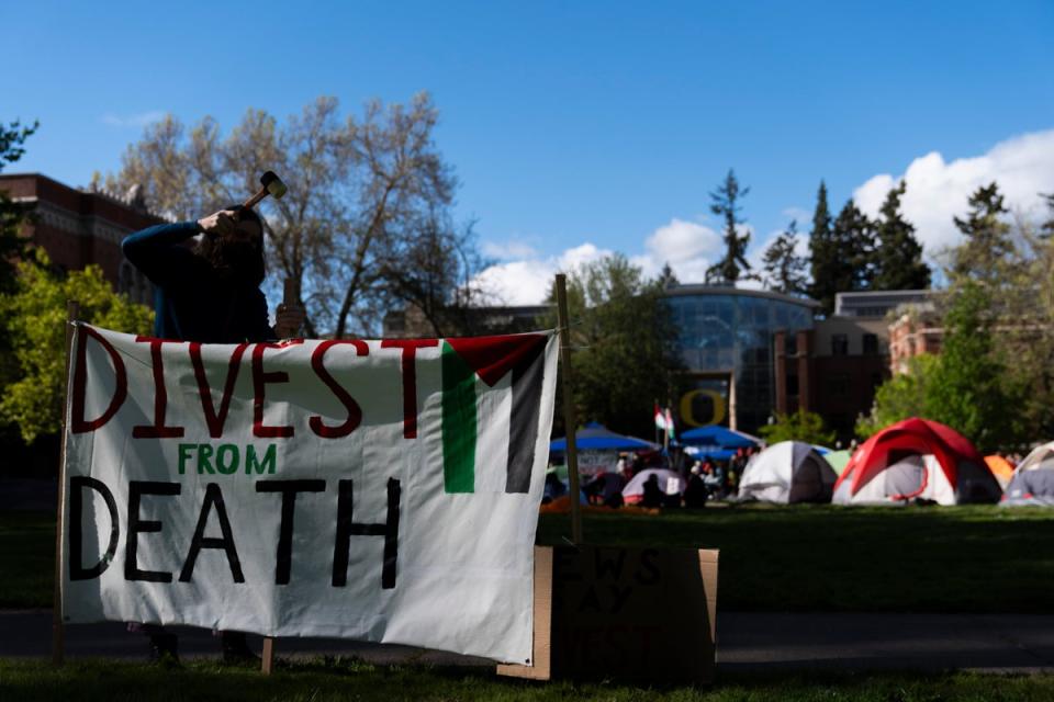 A student at the University of Oregon sets up a sign that reads “Divest from death” as students set up a tent encampment at the university to protest the Israel-Hamas war on Monday, April 29, 2024 (Copyright 2024 The Associated Press. All rights reserved.)