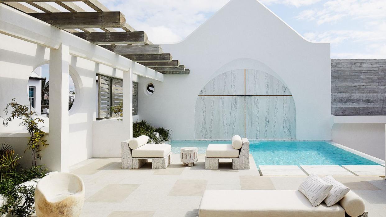  exterior of minimalist home with white walls pool and blue skies 