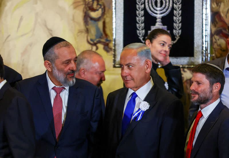 FILE PHOTO: Netanyahu looks at Member of Knesset Deri as they stand with members of the new Israeli parliament after their swearing-in ceremony in Jerusalem