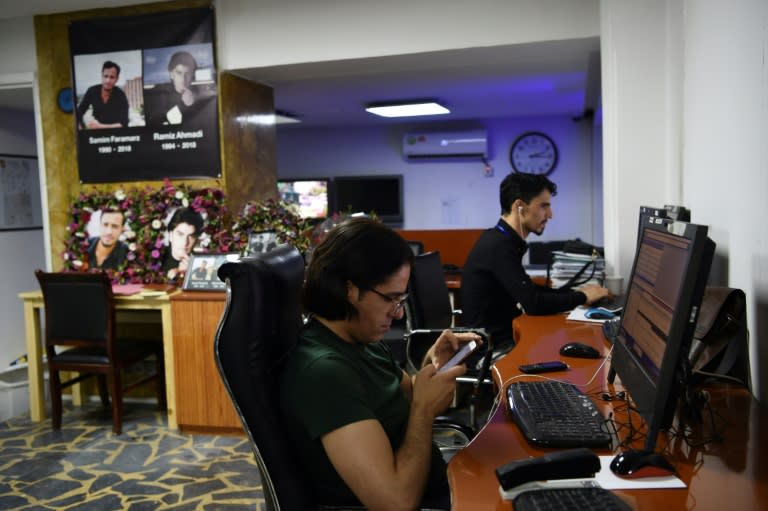 In the Tolo News office in Kabul, reporters work beside photo tributes to two colleagues killed in a suicide attack in September