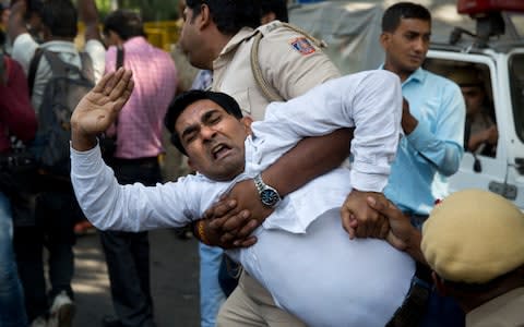 An Indian policeman takes away a Congress party worker during a protest against India's junior external affairs minister MJAkbar in New Delhi - Credit: Manish Swarup/ AP