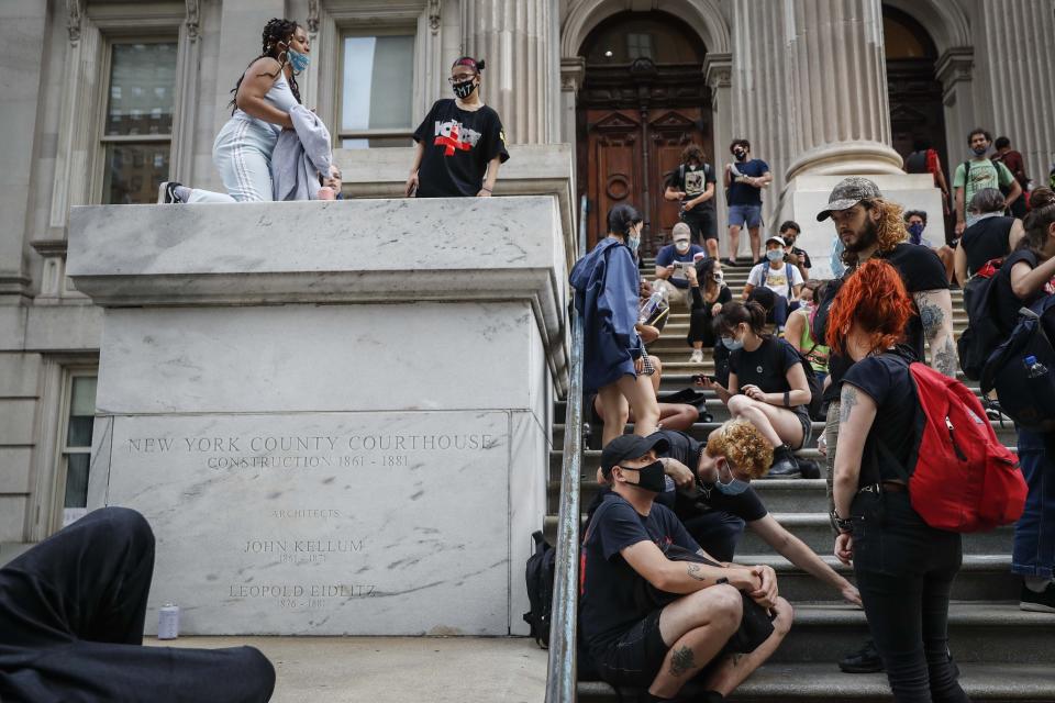 Protesters gather near an encampment outside City Hall, Tuesday, June 30, 2020, in New York. New York City lawmakers are holding a high-stakes debate on the city budget as activists demand a $1 billion shift from policing to social services and the city grapples with multibillion-dollar losses because of the coronavirus pandemic. (AP Photo/John Minchillo)