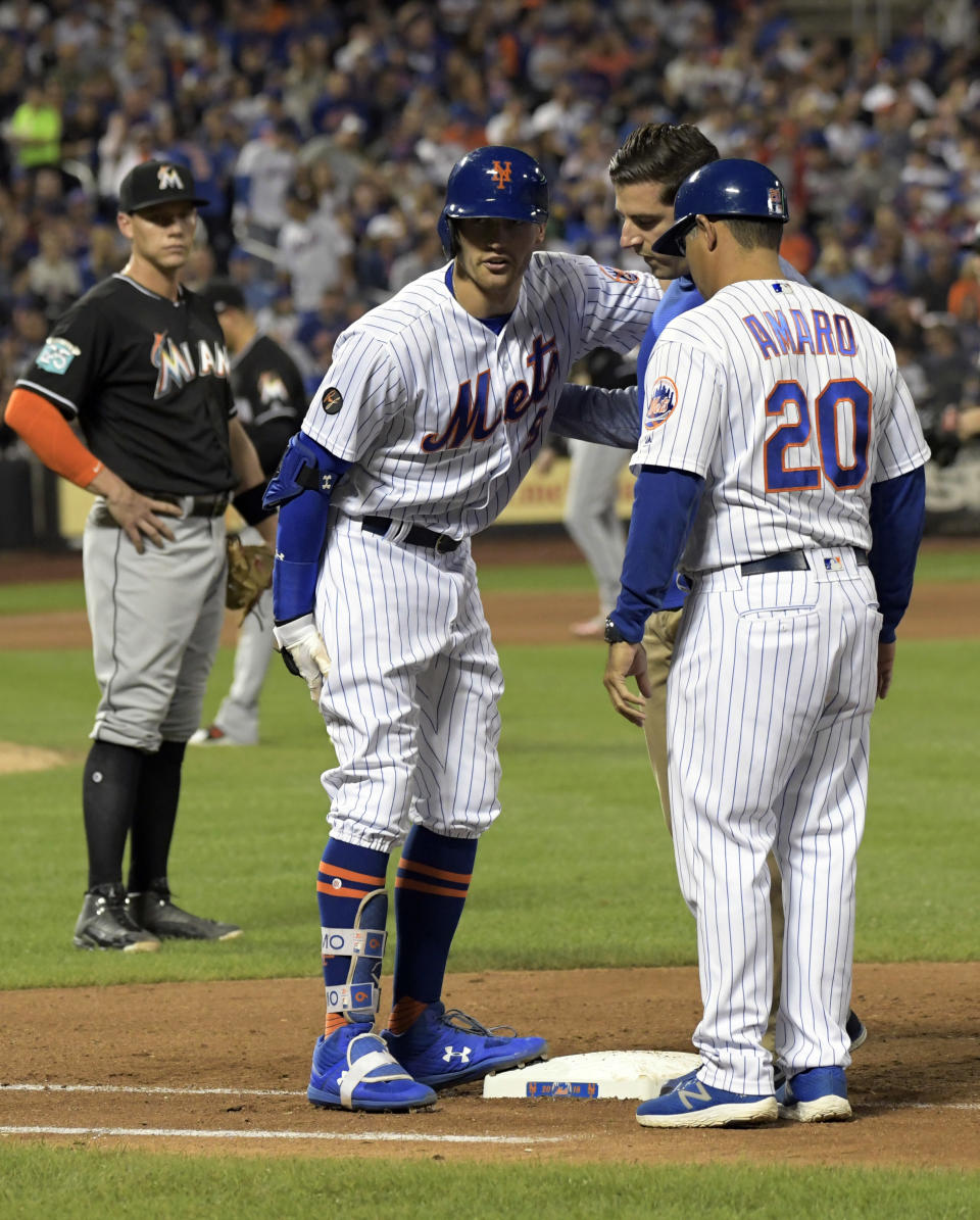 New York Mets' Brandon Nimmo (9) talks with first base coach Ruben Amaro Jr. (20) and a trainer after getting injured running out a single during the seventh inning of a baseball game as Miami Marlins first baseman Peter O'Brien, left, looks on Saturday, Sept. 29, 2018, in New York. (AP Photo/Bill Kostroun)