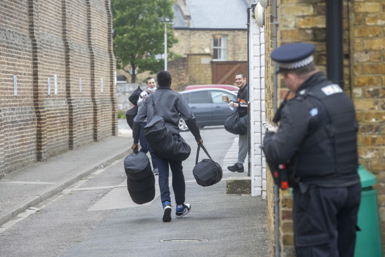 People seen outside a prison in London on 10 September as an officer looks on. (PA)