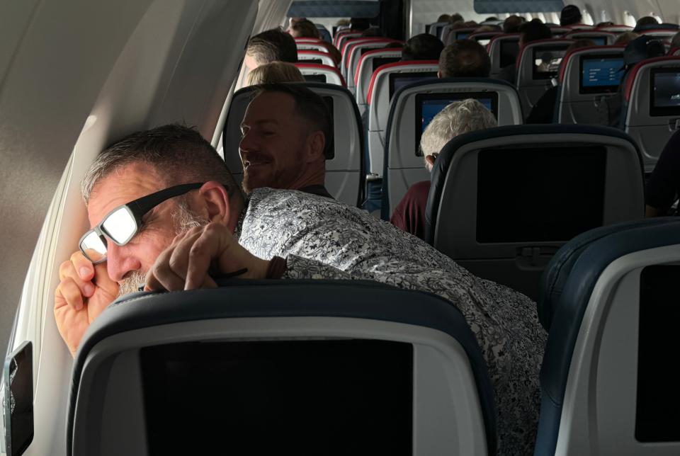 Titus Gambrell, of Athens, Georgia, looks out of his window after the captain announced the eclipse has started and is quickly moving from Mexico. The Delta flight 1218 from Austin to Detroit is flying at 640 mph due to a strong tailwind at 35,057 feet in order to stay in front of the moon as it starts to catch up to this flight.