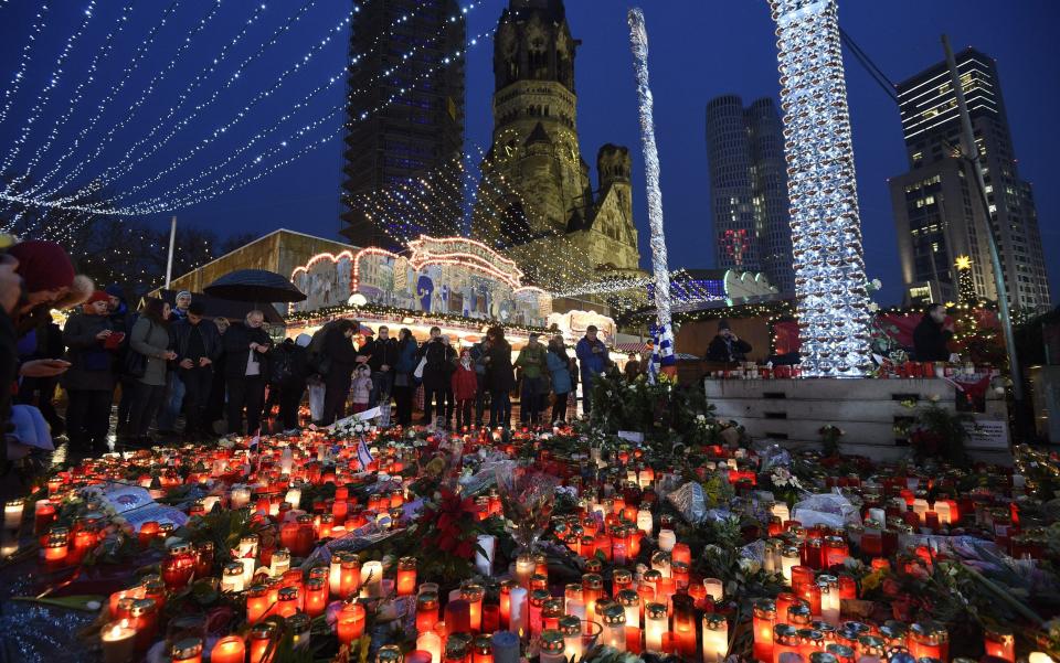 Lit candles illuminate the scenery at the re-opened Christmas Market on Breitscheidplatz square in Berlin - Credit: EPA/RAINER JENSEN