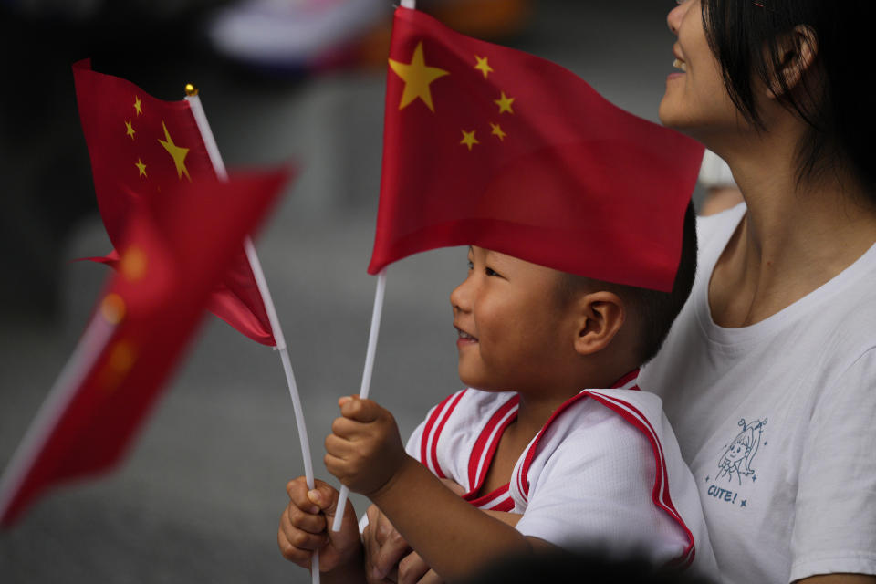 A young boy hods Chinese flags during the athletics competition at the 19th Asian Games in Hangzhou, China, Saturday, Sept. 30, 2023. (AP Photo/Vincent Thian )