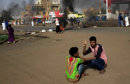 Sudanese protesters gesture near an erected barricade on a street, demanding that the country's Transitional Military Council hand over power to civilians, in Khartoum