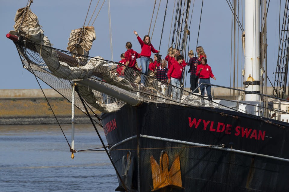 Dutch teens cheer on their schooner Wylde Swan after sailing home from the Caribbean across the Atlantic when coronavirus lockdowns prevented them flying, in the port of Harlingen, northern Netherlands, Sunday, April 26, 2020. (AP Photo/Peter Dejong)