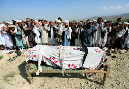 Relatives and residents pray near a coffin during a funeral ceremony of one of the victims after a drone strike, in Khogyani district of Nangarhar province, Afghanistan