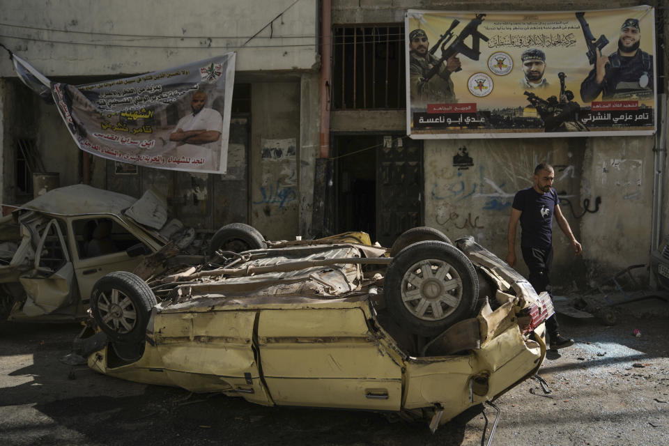 A man walks by destroyed cars in Jenin refugee camp in the West Bank, Wednesday, July 5, 2023, after the Israeli army withdrew its forces from the militant stronghold. The withdrawal of troops from the camp ended an intense two-day operation that killed at least 13 Palestinians, drove thousands of people from their homes and left a wide swath of damage in its wake. One Israeli soldier was also killed. (AP Photo/Nasser Nasser)