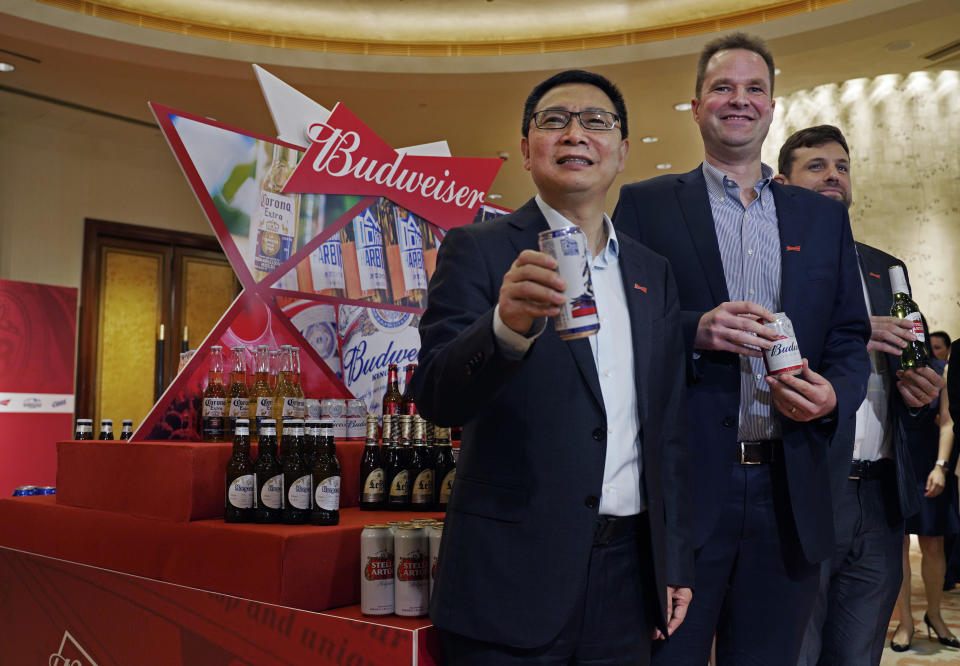 From left, Frank Wang, Executive Director, Jan Craps, Executive Director and CEO and Guilherme Castellan, Chief Financial Officer of Budweiser Brewing Company APAC Limited pose with products in Hong Kong Tuesday, Sept. 17, 2019. AB InBev, the world's largest brewer that produces Budweiser and Corona, has revived plans to list its Asian business in Hong Kong despite persistent pro-democracy protests but halved the size of its initial public offering. (AP Photo/Vincent Yu)