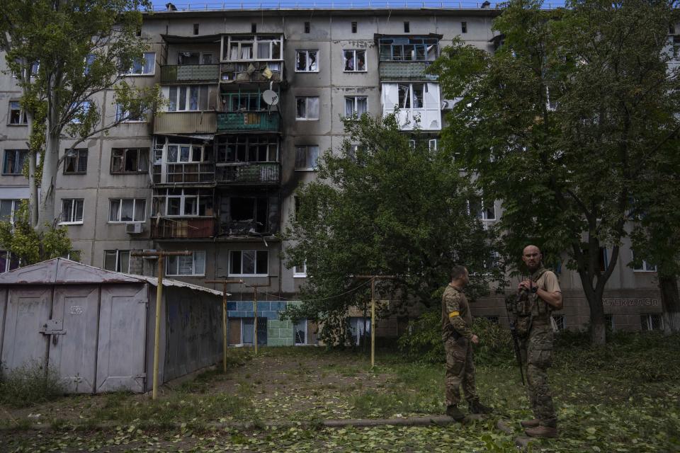Ukrainian soldiers stand in front of a five-story residential building damaged from a rocket attack on a residential area, in Kramatorsk, eastern Ukraine, Tuesday, July 19, 2022. (AP Photo/Nariman El-Mofty)