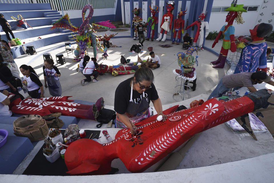 Artist Adriana Aldaraca prepares her paints to craft a devil-like cardboard figure popularly known as "Judas," for the upcoming "Burning of Judas," celebration, at the Santa Maria La Ribera Cultural Center in Mexico City, Wednesday, April 5, 2023. Originally, the burning figures were effigies of Judas Iscariot, the apostle who betrayed Jesus, according to the Biblical account of the days leading up to Christ's crucifixion. Nowadays, though, Mexican artisans shape their Judas like red, horned devils or other characters considered evil by society. (AP Photo/Marco Ugarte)