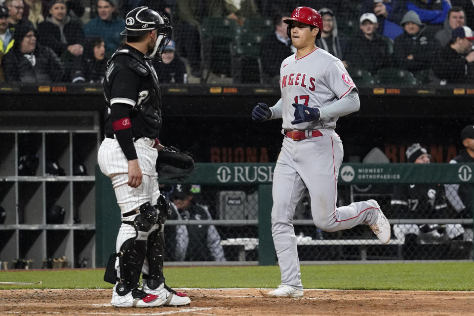 Los Angeles Angels' Shohei Ohtani, right, of Japan, scores on a one-run double by Anthony Rendon as Chicago White Sox catcher Yasmani Grandal looks to the dugout during the sixth inning of a baseball game in Chicago, Friday, April 29, 2022. (AP Photo/Nam Y. Huh)